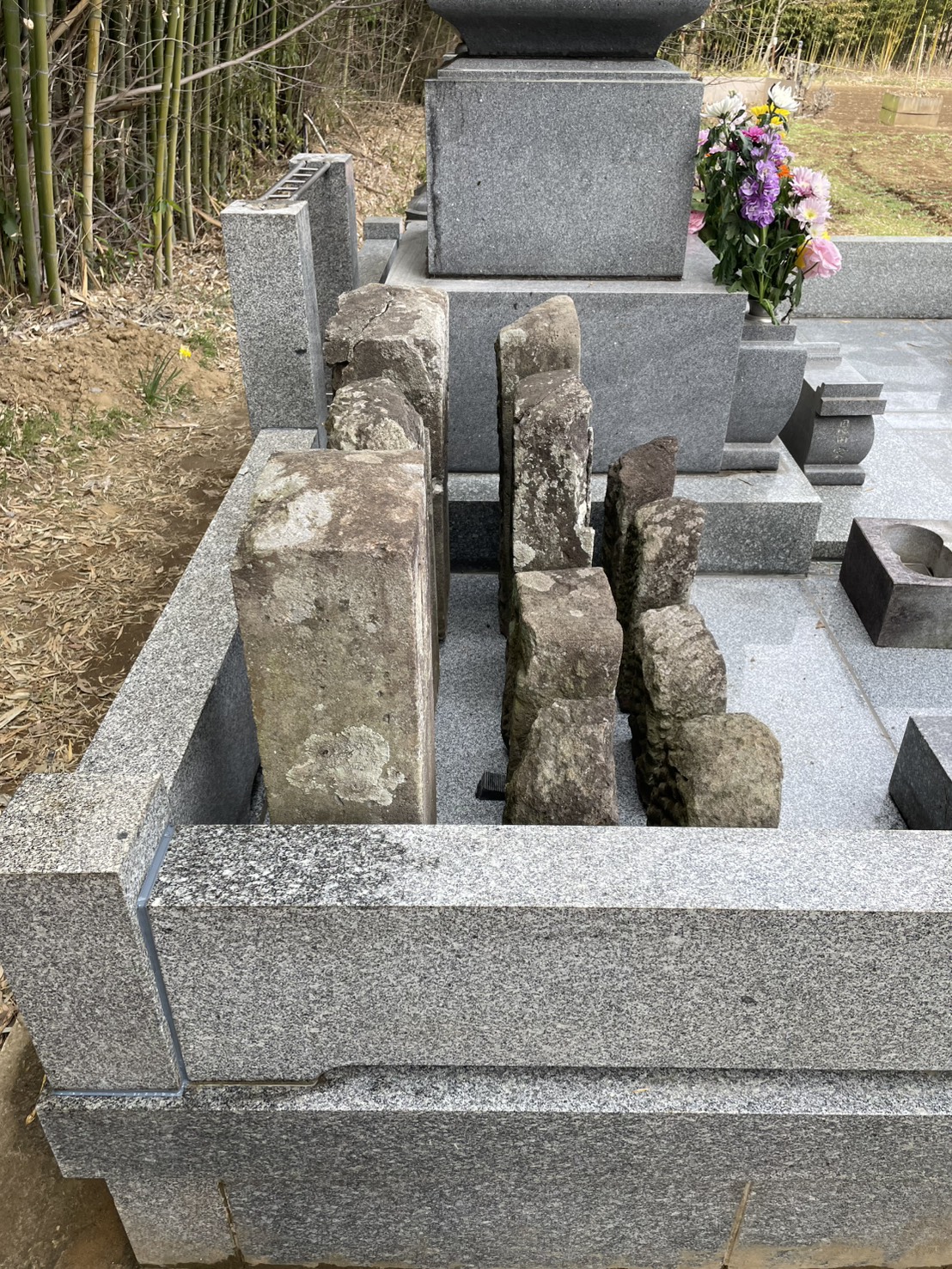 ご先祖様の石塔を仮並べし、掃除道具が入る間隔を確認してから据え直す様子