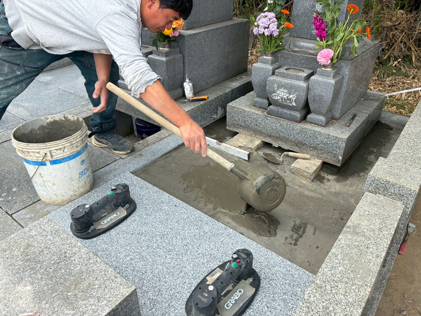 コンクリートの上に敷石を一枚一枚、水平を確認しながら設置する様子