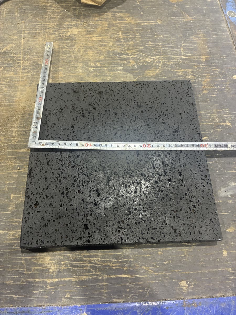 加工前の溶岩石プレートに定規を当てて30cm角の大きさを測っている様子